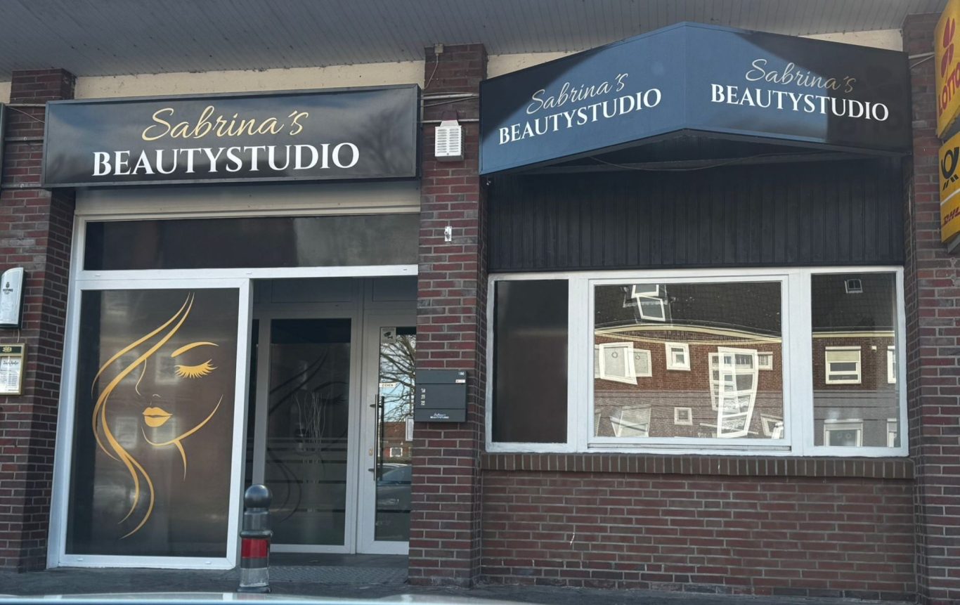 Eingang zu Sabrina's Beautystudio Schaufenster eines Schönheitssalons mit schwarzem Schild und goldenen Akzenten.